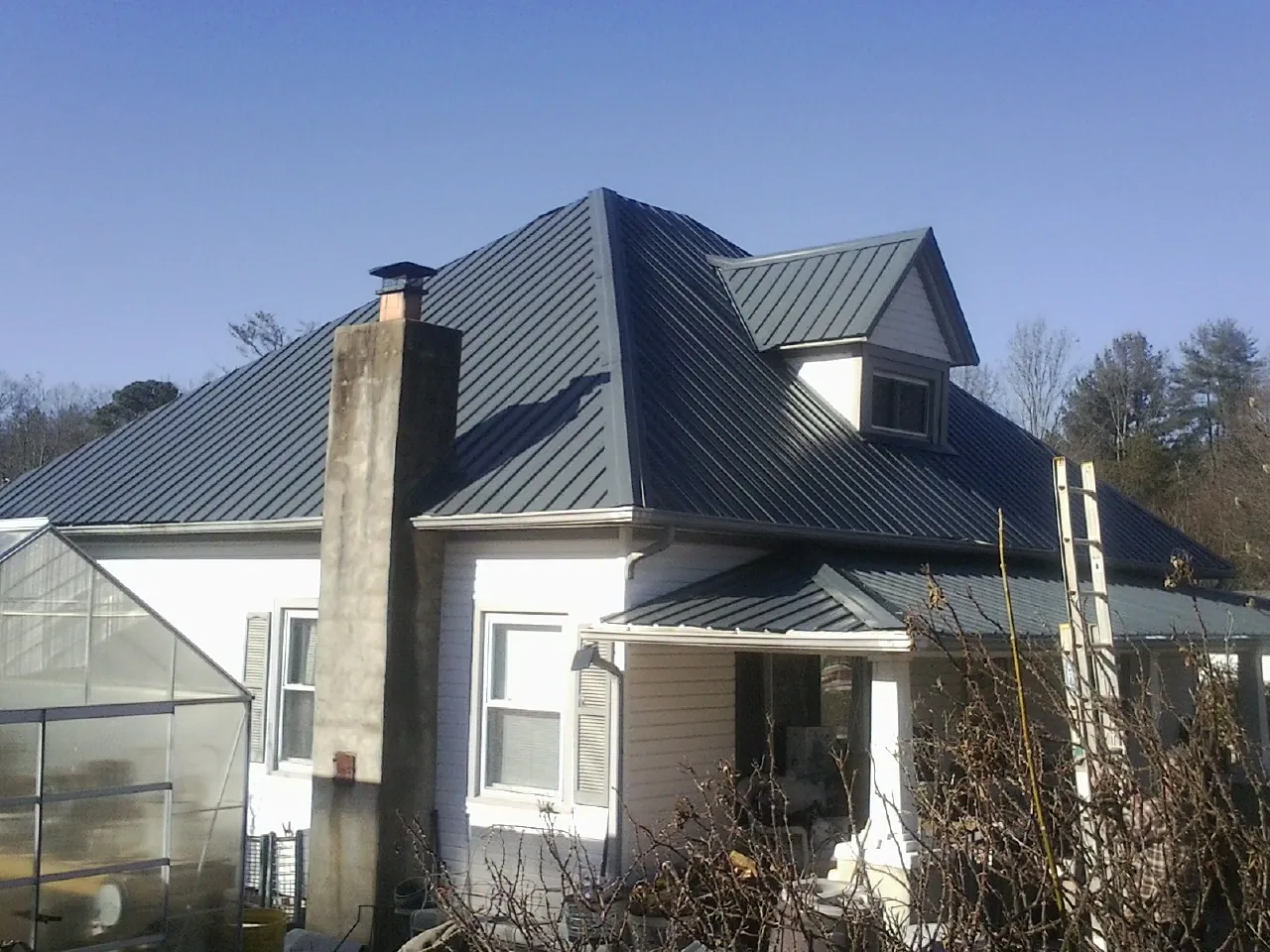 Dark blue standing seam metal roof on a white farmhouse with dormer — Slate & Tile Roof Repair by Roofing Brothers in Kulpmont