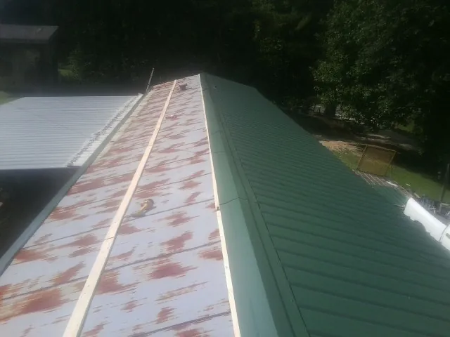 Old rusted panels beside newly installed green metal roofing — Wind Damage Roof Repair by Roofing Brothers in Kulpmont