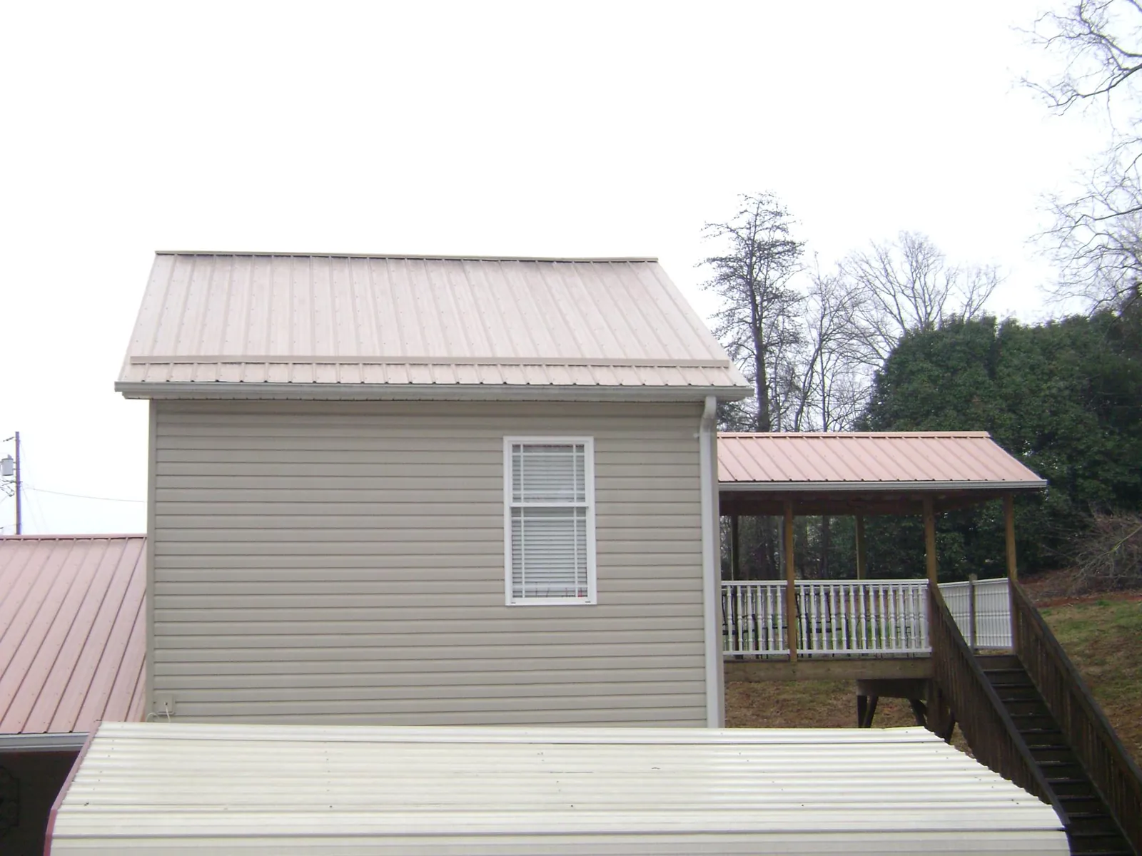Tan metal roofs on a two story addition and attached porch, from a Roof Replacement job in Kulpmont