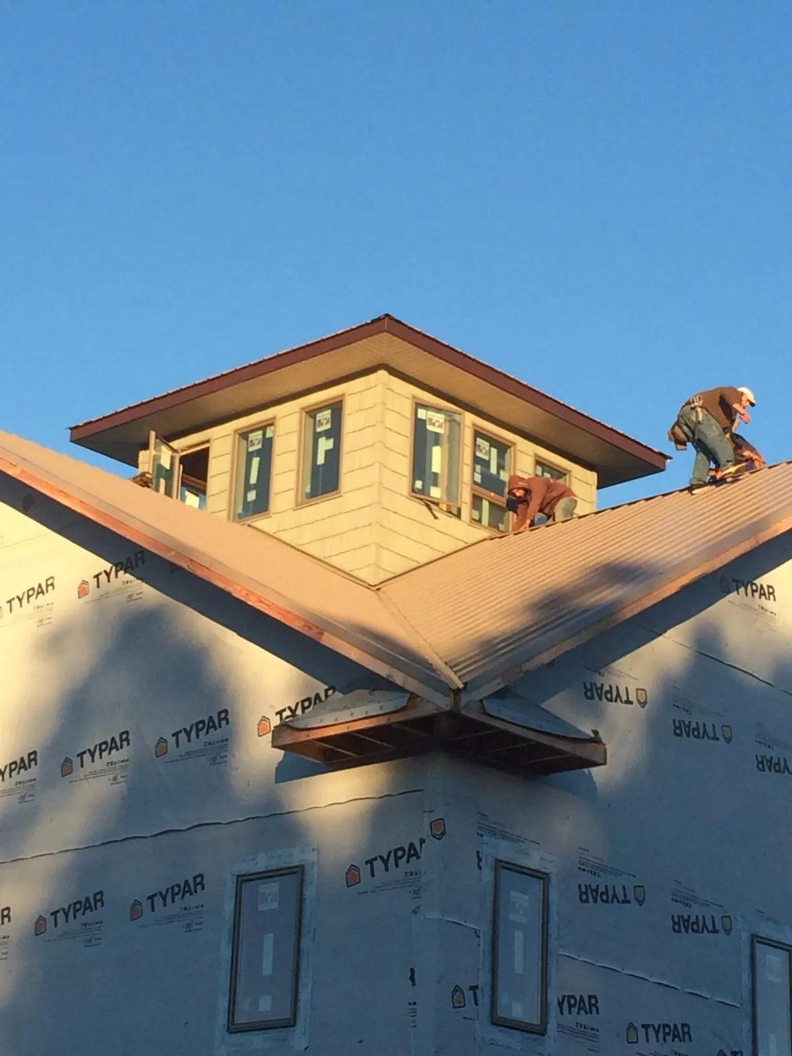 Roofers working around a rooftop cupola on a new metal roof at sunset — Roof Waterproofing in Kulpmont by Roofing Brothers